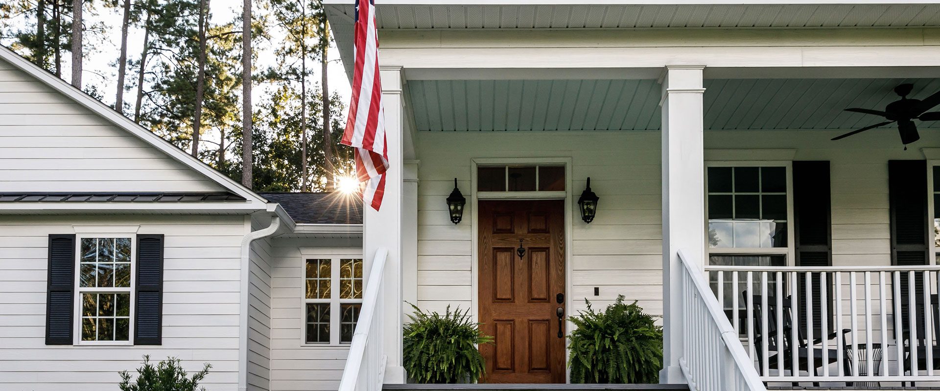 A house with american flag on the front porch.